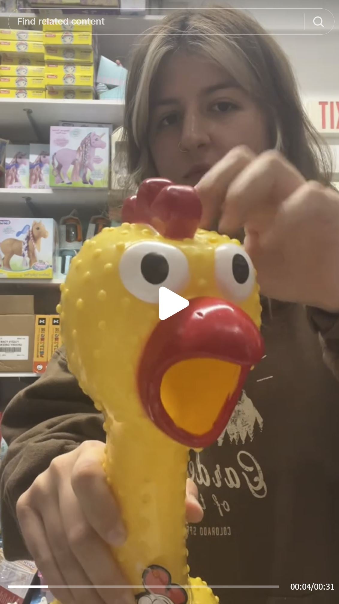 A person squeezes the 🐔 GIANT 27" Rubber Chicken, the biggest and loudest squeaky toy, in a store with toy shelves in the background.