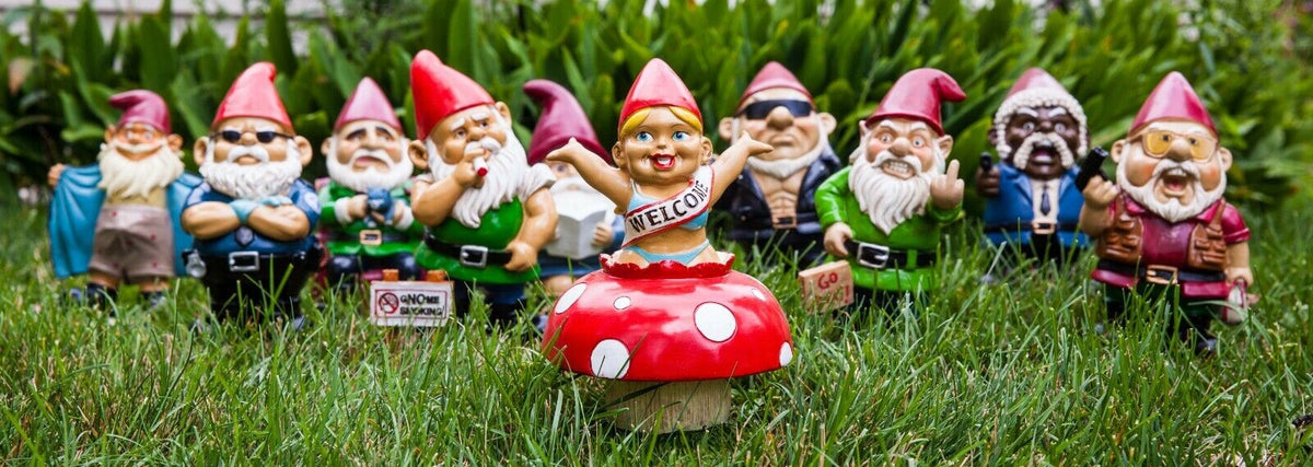 A group of whimsical garden gnome statues stands on the grass, with one in the front wearing a "Welcome" sash and standing on a red mushroom with white spots. The prominent figure in this amusing scene is the DONALD TRUMP GARDEN GNOME - Outdoor Home Yard Lawn Statue Sculpture by BigMouth.