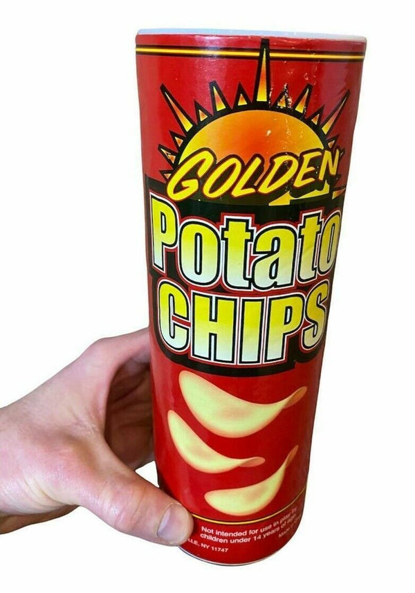 A hand holding a red canister of "Potato Chips Snake Can Spring Pop" from Golden brand, adorned with images of chips and a sun logo on the front, conceals the ultimate classic gag—it's actually a prank toy perfect for parties!