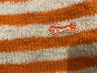 Close-up of a fabric with orange and white horizontal stripes, showcasing a small embroidered design of an orange and white jumping cat—perfect for the Stylish Genuine Le Tigre Knit Hat Winter Beanie made from 100% acrylic.