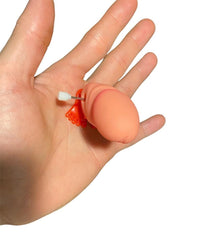 A hand holding a small, flesh-colored object with a pin and several red loops attached to it, set against a plain white background. Perfect for kids' birthday parties, this intriguing decoration adds a whimsical touch to any celebration.

Rewrite using the product data: 

A hand holding the "1 Jumping Boobie & 1 Pecker - Wind up Set," set against a plain white background. This funny novelty adult gift is perfect for hen parties and adds a whimsical touch to any celebration.