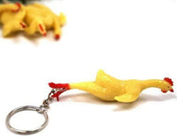 Displayed on a white surface is a keychain featuring a yellow rubber chicken attached to a metal ring. In the background, another rubber chicken appears blurred, highlighting these 3" Rubber Stretch Rubber Chicken Key Chains as quirky and fun party prizes. Sold in sets of one dozen under the name "12 TOTAL 3" Rubber Stretch Rubber Chicken Key Chain - Gag Gift Joke (1 dozen)," they make for perfect gag gifts.