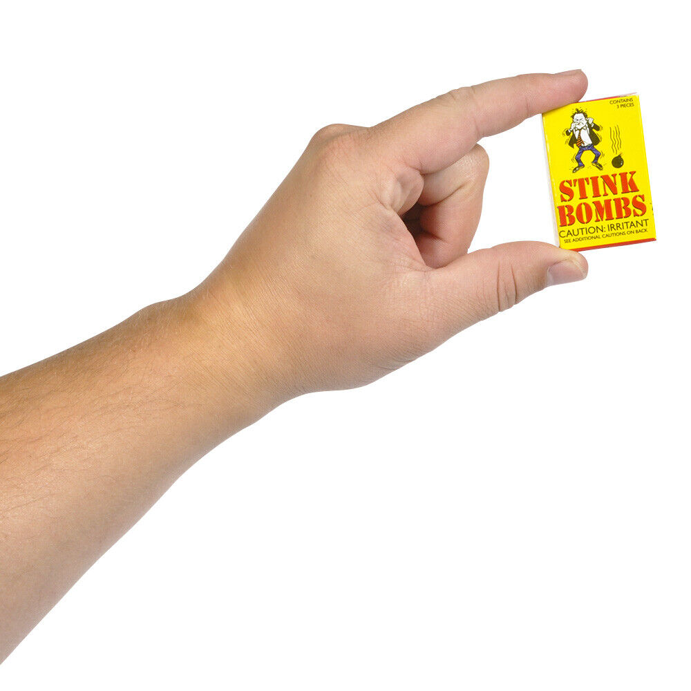 A hand holding a small yellow box labeled "1 Case of 36 Stink Bombs + 3 Fart Bomb Bags ~ Combo Set" with a caution warning, perfect for prank items enthusiasts.