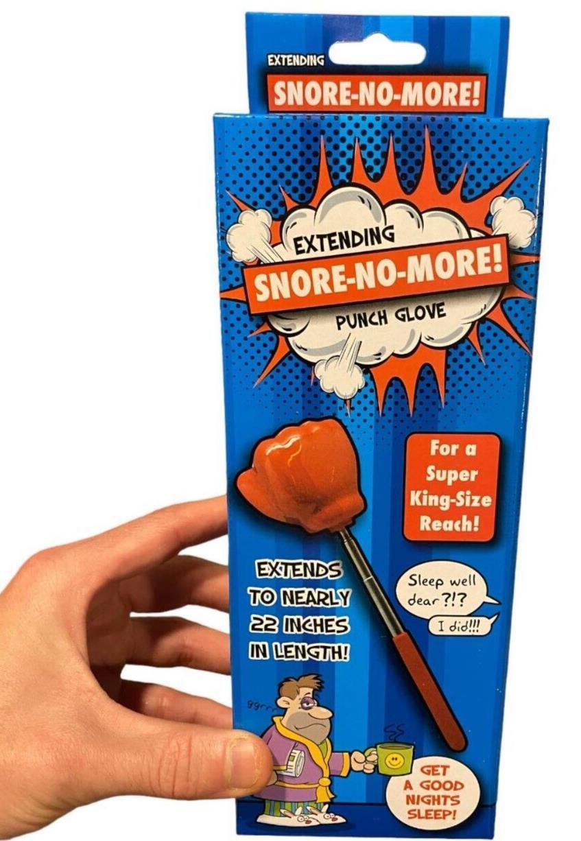 Someone holds a Giant 22" Extending Boxing Punch Glove - Snore-no-More! package with blue and orange colors, humorous text, and cartoon graphics—perfect for a funny gag gift.