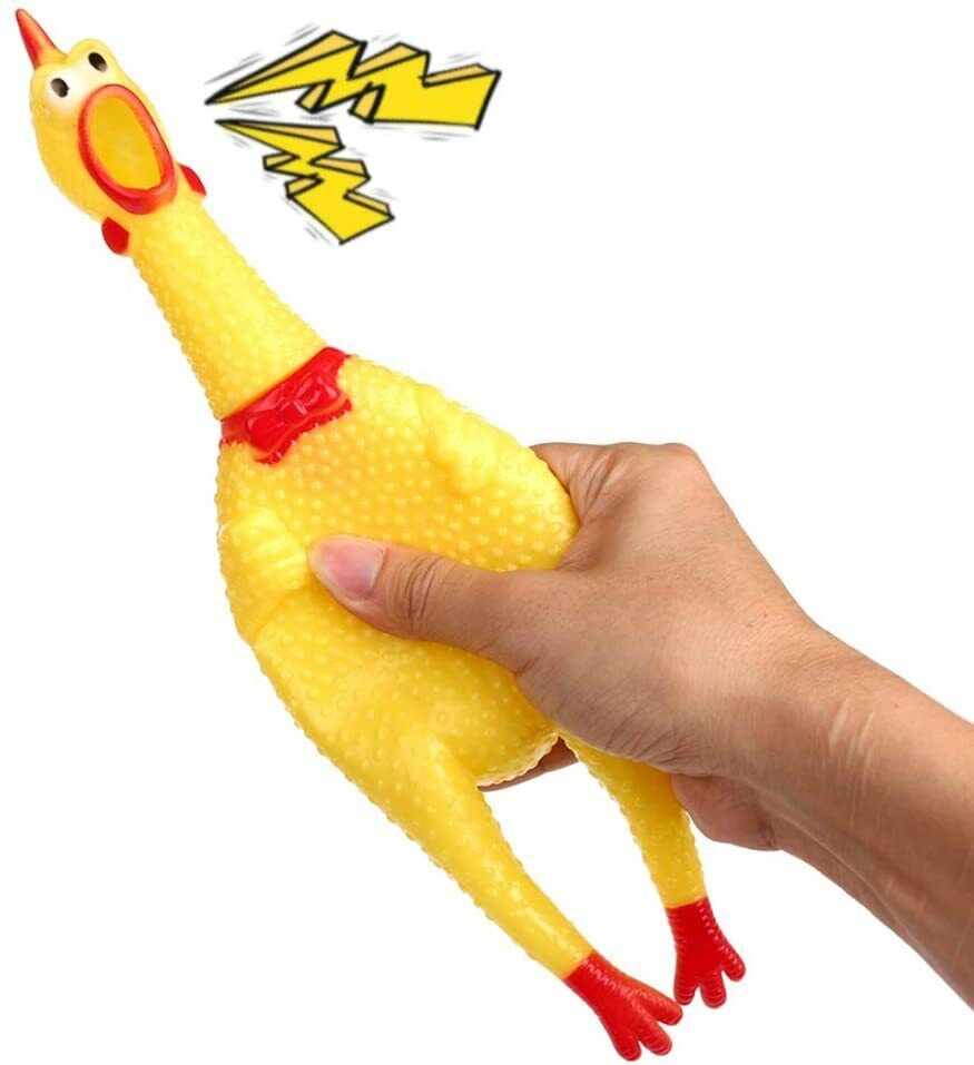 A hand squeezing one of the classic yellow rubber chickens from the combo set, complete with a red bow tie, causing it to make a loud squeaking noise.