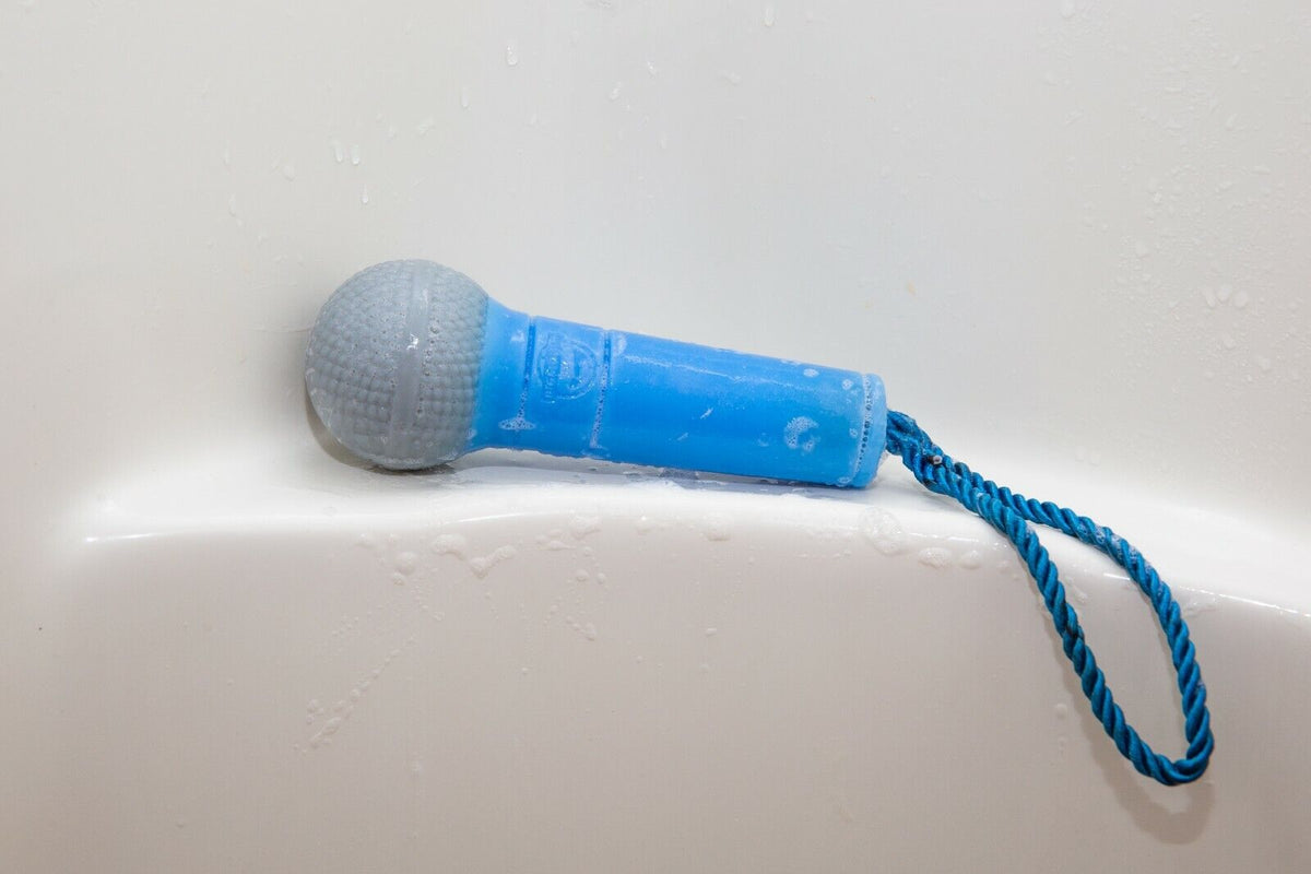 Close-up of the Microphone Soap On Rope - Rock on while cleaning up your butt! by BigMouth Inc, featuring a blue design with a braided cord, resting on a wet surface—perfect for shower concerts.