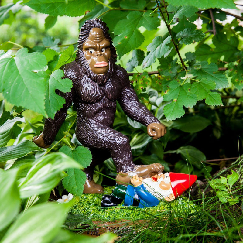 🦶The BigFoot Gnome Wrecker – Giant Garden Gnome Smasher adds quirky charm to your garden decor, featuring a plastic figurine stomping a gnome among green plants.