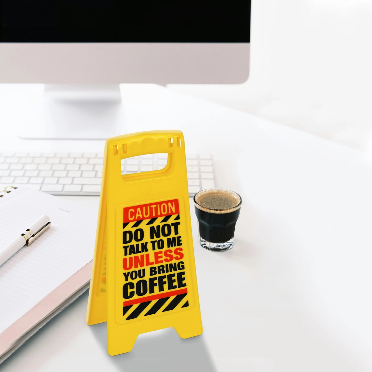 The ⚠️ Funny Warning Bring Coffee Desk Sign ☕️—reading "DO NOT TALK TO ME UNLESS YOU BRING COFFEE"—sits by a coffee cup, notebook, pen, and computer; ideal as a quirky office decor or humorous gag gift.