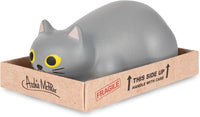 Meet the Purrrly Kitty Cat in a Box Stress Squeeze Squish by Archie McPhee—a gray cat loaf toy featuring large yellow eyes, cozily tucked inside a cardboard box marked "Fragile" and "This Side Up - Handle with Care." Perfect for easing stress after a hectic day.