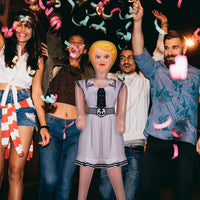 A group of people celebrating at night with colorful confetti in the air and an Inflatable Judy + John Inflate a Date Bachelor/Bachelorette Party Blow Up Doll joining the fun.