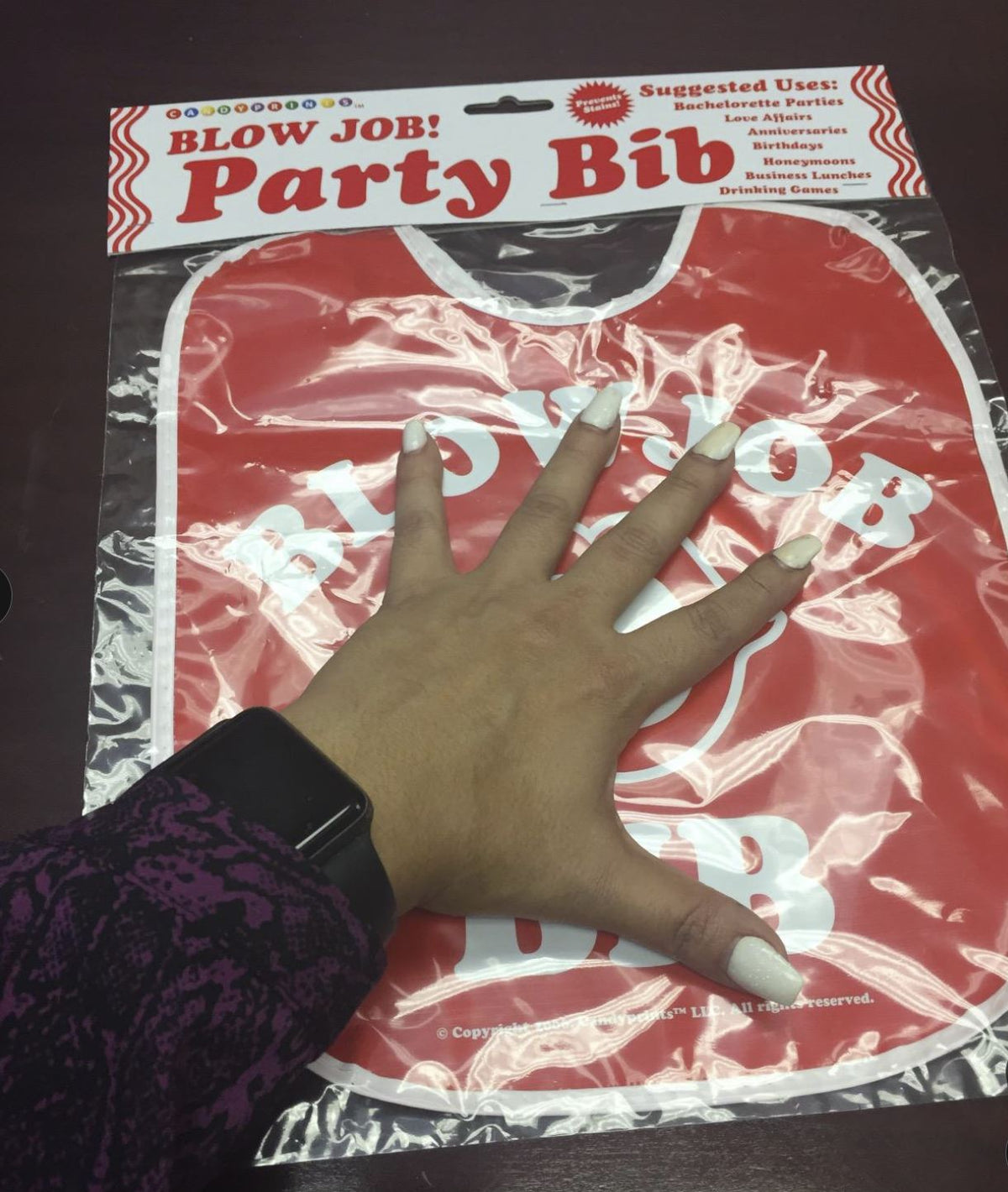 A manicured hand holds the Blowjob Bib Bachelorette Party Favor 💋—an adult gag gift perfect for bachelorette parties, anniversaries, and more.