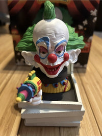 The Killer Klowns 🤡 Shorty in Pizza Box Bobblehead Statue Figure by Royal Bobbles features Shorty with green hair and bold makeup popping from a box, aiming a colorful toy ray gun, just like in Killer Klowns from Outer Space.