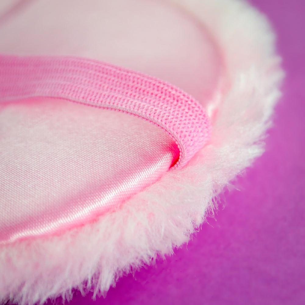 Close-up of THE BITCH IS SLEEPING pink sleep mask with fluffy trim and an elastic strap, resembling a novelty gift, set against a purple background.