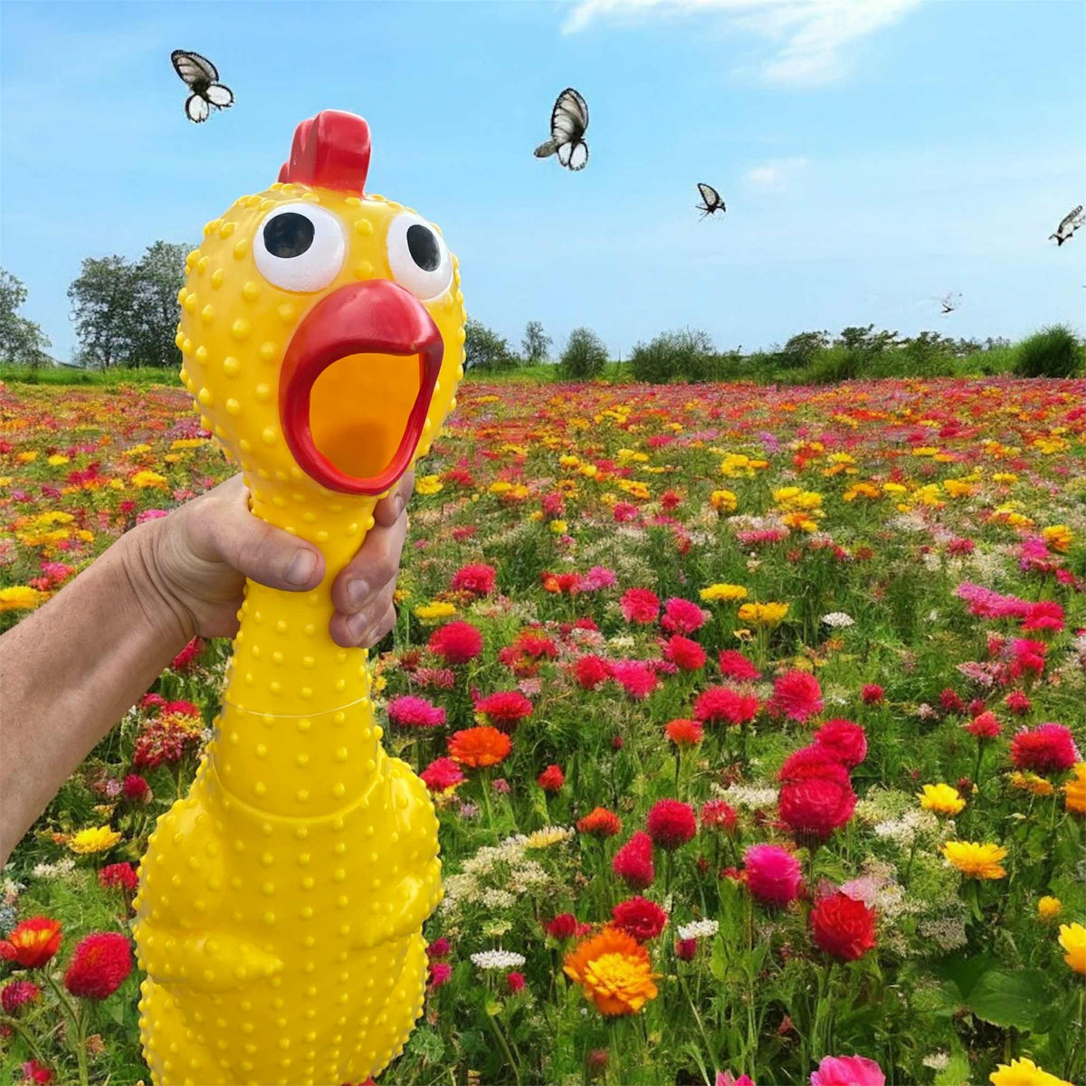 A hand holds the 🐔 GIANT 27" Rubber Chicken—the biggest, loudest squeaky toy—in a field of flowers with butterflies in the sky above, creating a playful and hilarious scene, perfect for a gag gift.