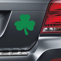 A 12 Shamrock Irish Clover Leaf Magnet from the Saint Patrick's Day collection, radiating Irish pride, is displayed on the rear of a gray car near the taillight.