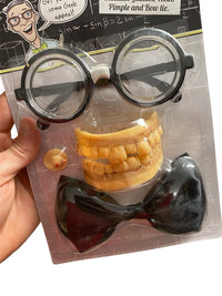 Instant Geek Costume Kit 🤓 includes glasses, oversized fake teeth, a black bow tie, and a yellow pimple button—perfect for nerd dress up or as a funny gag gift. Comes in packaging held by a hand.