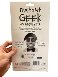 A hand holds the Instant Geek Costume Kit package, featuring illustrations of glasses, fake teeth, bow tie, and pimple—funny gag gifts and perfect accessories for a nerd dress up set—with witty descriptions and novelty warnings.