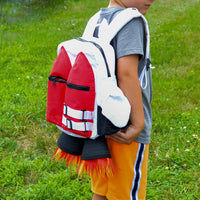 A child stands on grass wearing a grey shirt, yellow athletic shorts, and the Kids Jetpack Backpack Rocket School Bag 🚀—a space astronaut costume travel gift with flame details.