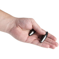 A hand holding two compact, black, metallic oval items resembling the Magnetic Rattlesnake Eggs - 2 Pack - Magic Fidget Stress Toy for Kids to Adults.