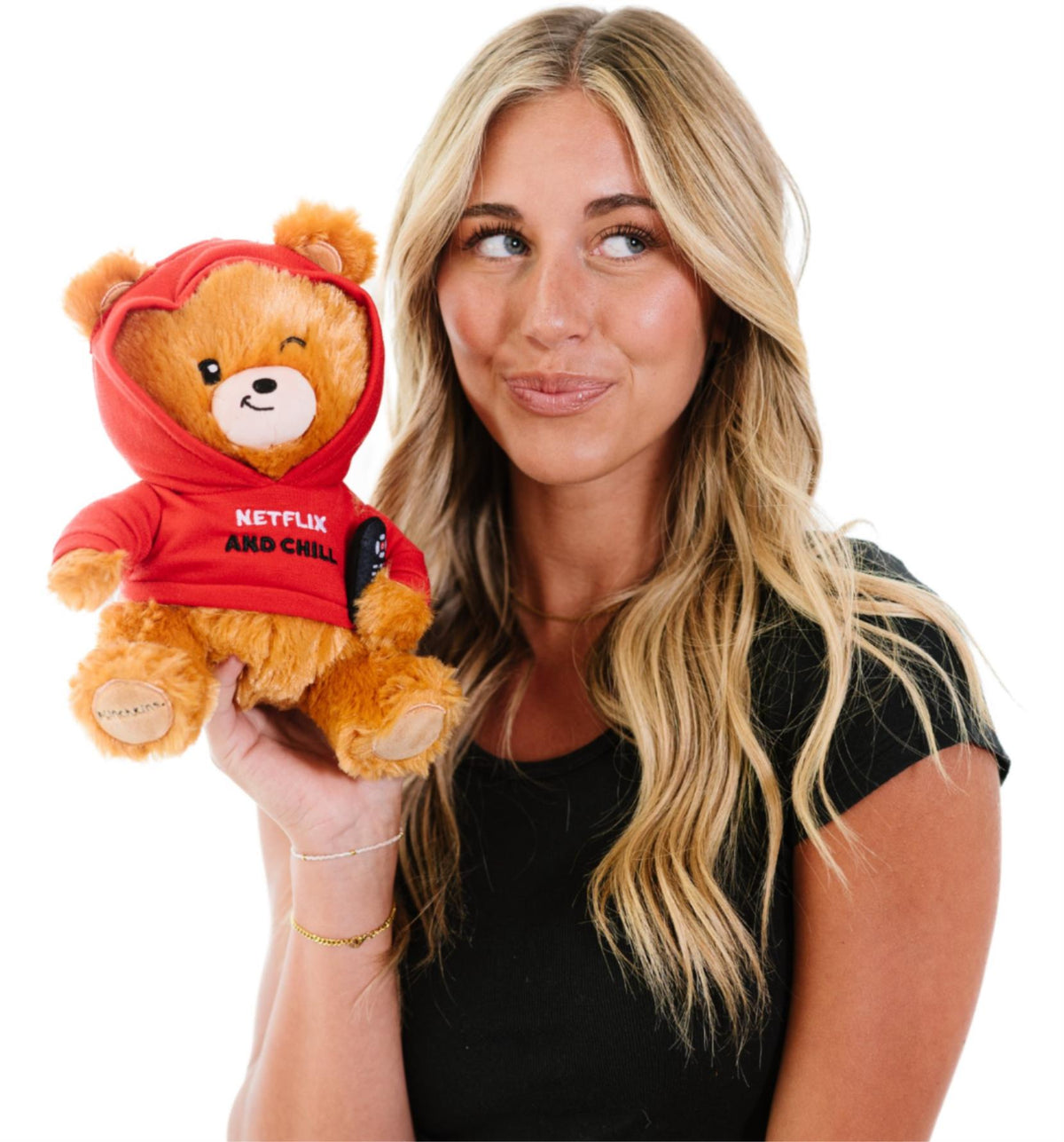 A woman with long blonde hair holds the Punchkins "Netflix & Chill" Teddy Bear Plushie—an adorable cuddly gift for movie fans—in a red hoodie, against a white background.