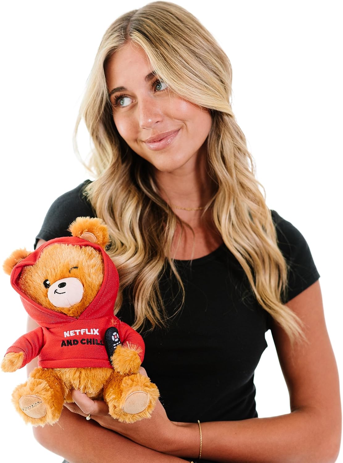 A woman with long blonde hair in a black t-shirt holds the Punchkins "Netflix & Chill" Teddy Bear Plushie, a cuddly movie fan’s gift in a red hoodie, against a white background.