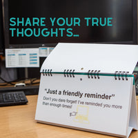 The "As Per My Last Email" desk spiral flip book, featuring humorous office message table signs with a "Just a friendly reminder" touch, sits next to a computer monitor and keyboard. This novelty item adds office humor and makes for the perfect sarcastic translations gift for those familiar with the chaos of daily deadlines.