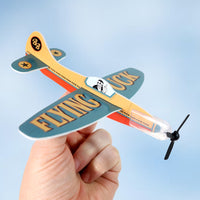 A hand holds the ✈️🤣 FLYING FU%K – The Mini Plane Glider That Says It All! 🙌😂 Adult Gag Joke, making it the ultimate funny gift for anyone who loves a good laugh.