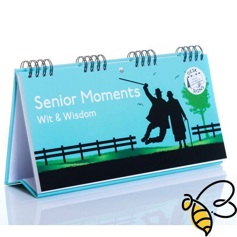 The "Senior Moments - Desk Spiral Flip Book – Over Hill Message Table Desk Signs" is an ideal choice for a humorous retirement gift or as a quirky addition to white elephant exchanges. It features a silhouette of two people, one with a cane, against a blue backdrop.