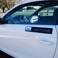 A white car door boasts a "RETRO Slide to Unlock Magnet with an arrow, reminiscent of a smartphone lock screen. This high-quality 17" magnet from Big Mouth Inc adds a fun and modern touch to your vehicle.