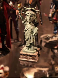 The Statue of Liberty Bobblehead Figure 🗽 – Premium Lifelike Collectible Decor Gift is displayed on a reflective surface, surrounded by superhero action figures for a one-of-a-kind collectible display.