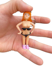 A hand holding the Saucy Suzie Flashing Stripper Keychain – a funny adult gag gift peepshow toy with orange hair, pink shoes, and sunglasses pulled down to flash her chest.