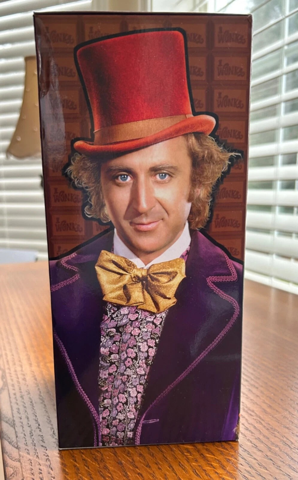 A cardboard box houses the Willy Wonka Bobblehead Statue – Gene Wilder Collectible Figure by Royal Bobbles, featuring him in a red top hat, purple coat, and gold bow tie before a "Wonka" logo background.